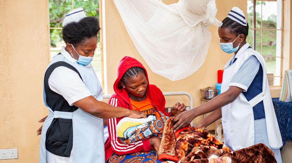 A new mother (M) receiving post-natal check-ups at a facility supported through the FP-ASRH Programme in Central Province