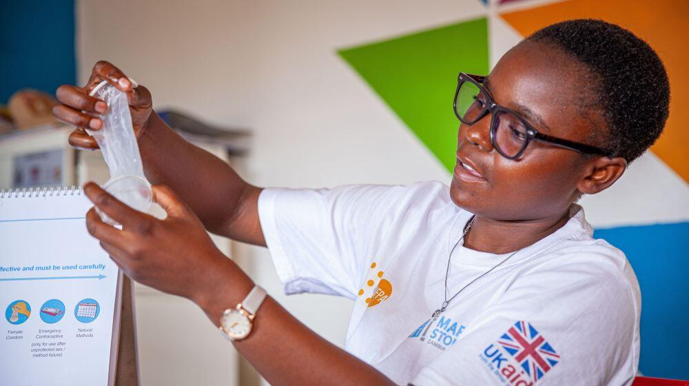 A peer educator at Kapiri Mposhi district hospital, demonstrating condom use to young people. 